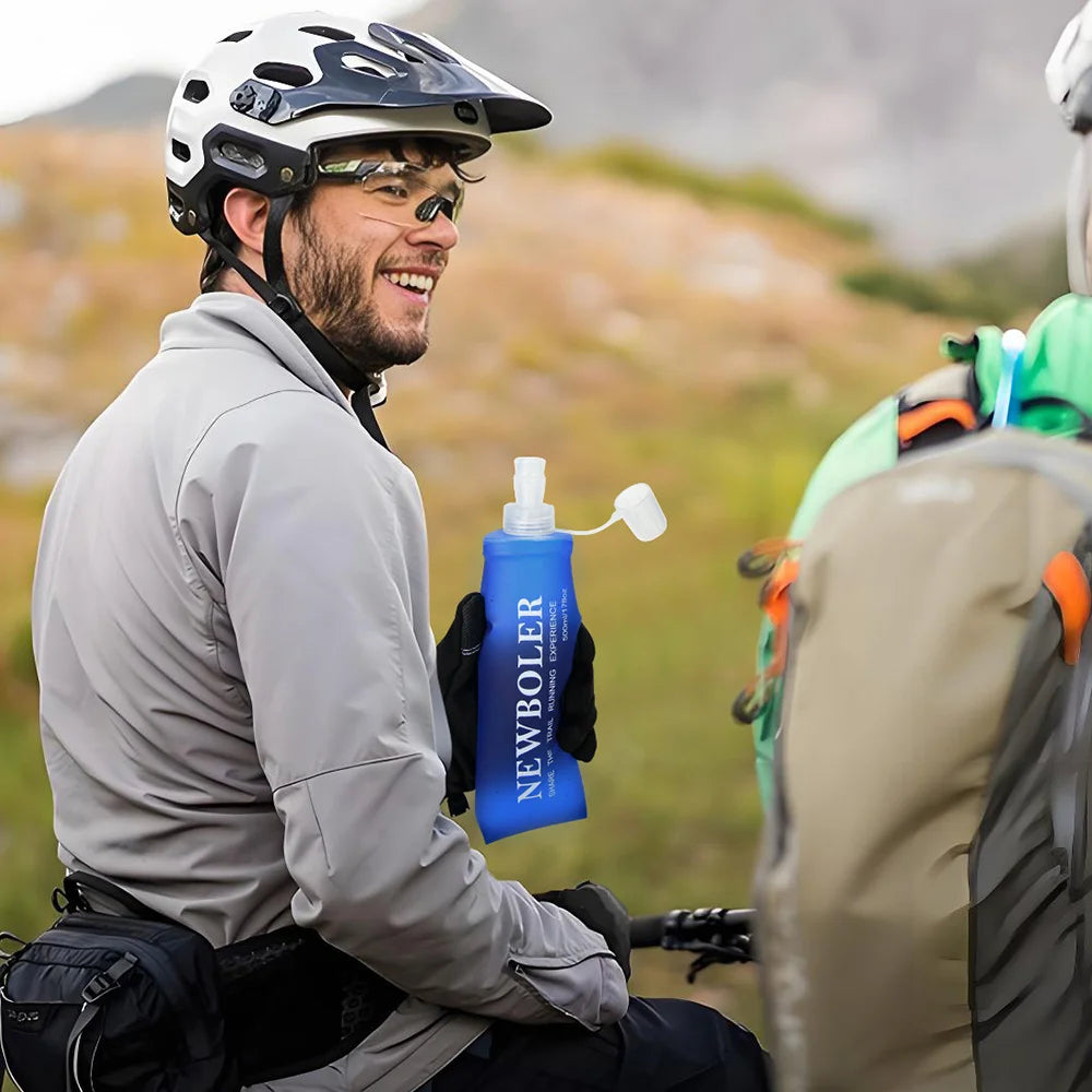 Smiling cyclist wearing a lightweight hydration vest for running holding a blue Newboler water bottle outdoors